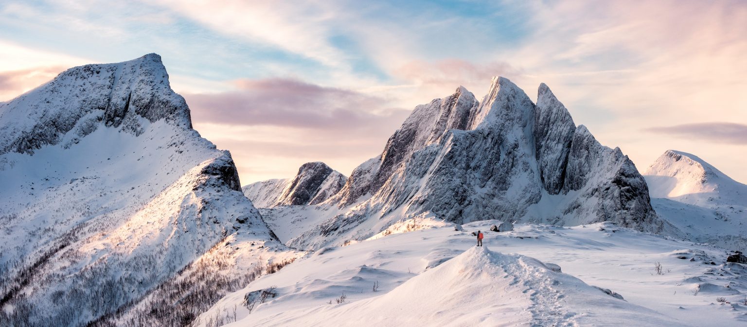 Panorama of Mountaineer standing on top of snowy mountain range